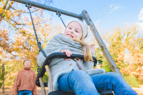 Beautiful smiling girl with her mom on a swing in the park playg © Jarek Pawlak