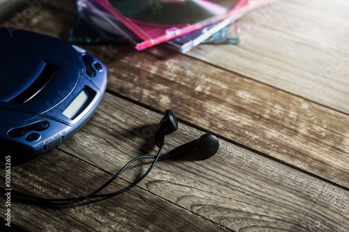 CD player with disc and earphones on wooden plank