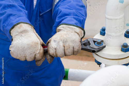 Close-up image of human hand fixing and stop leak flange by wrench in oil and gas process