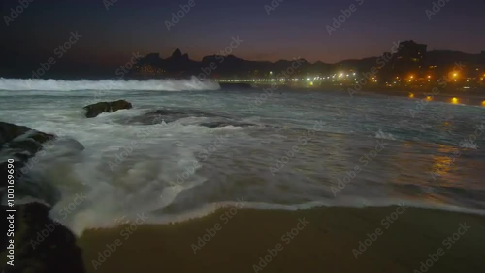 Slow motion, pan right of waves crashing against Ipanema beach at night Slow motion, pan right of waves crashing against Ipanema beach at night