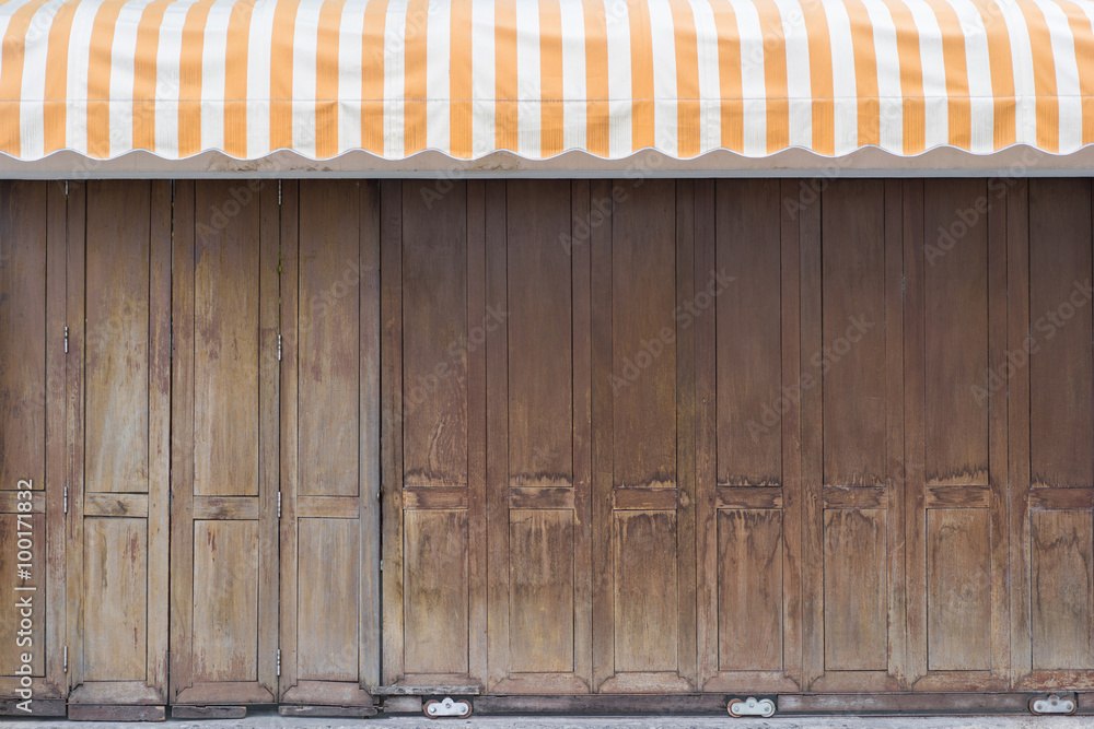 Fototapeta premium Vintage wooden gate with yellow stripe awning