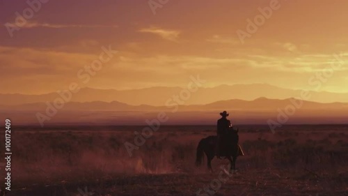  Lone western cowboy riding a horse at sunrise sunset, slow motion