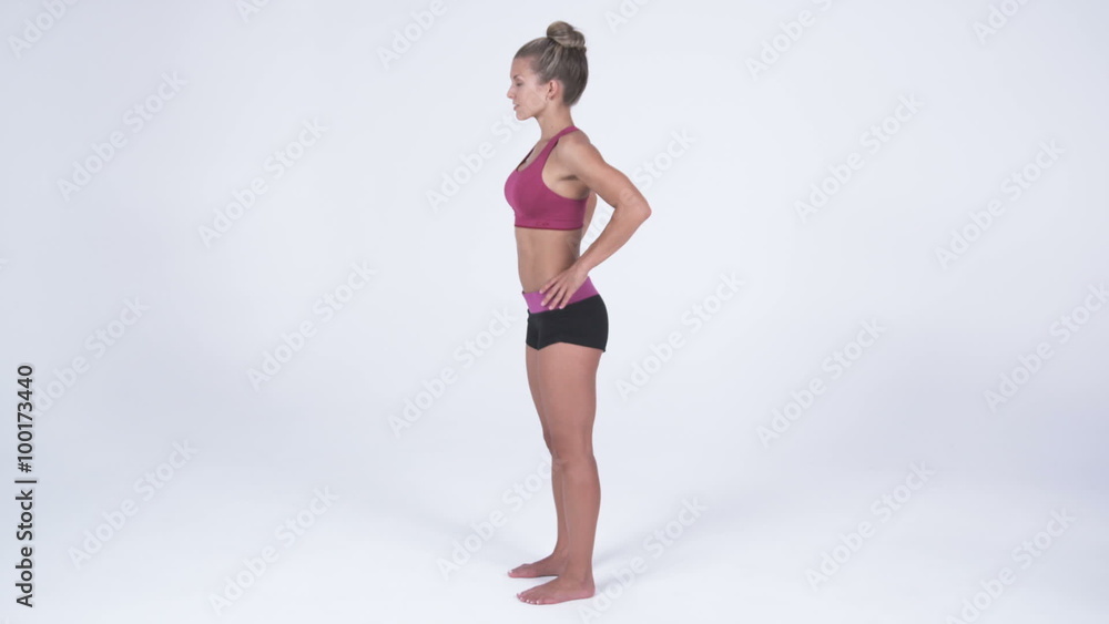 Left side view of a young woman in yoga attire, putting hands on hips Left side view of a young woman in yoga attire, putting hands on hips