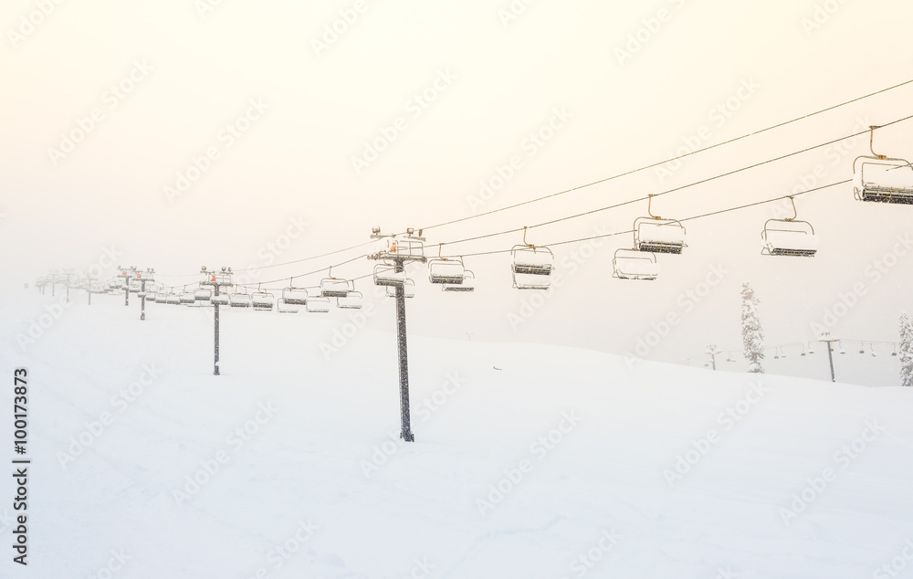 scene of ski lift with seats  over the mountain and paths from skier.