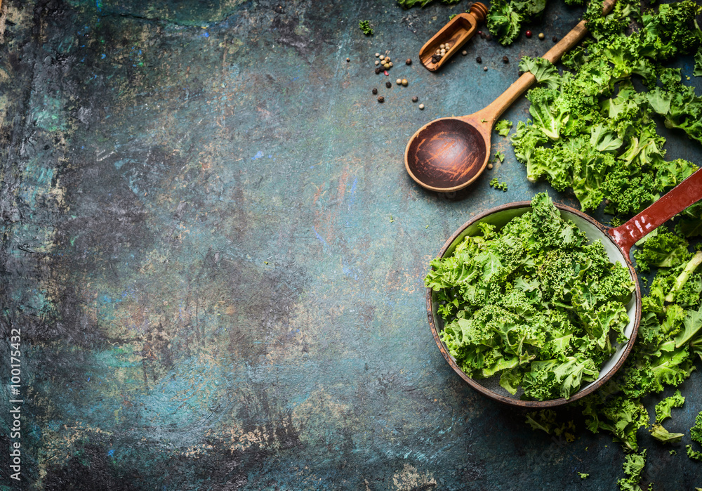 Fresh kale in cooking pot with wooden spoon on  rustic background, top view, border. Healthy food or diet nutrition concept. - obrazy, fototapety, plakaty 
