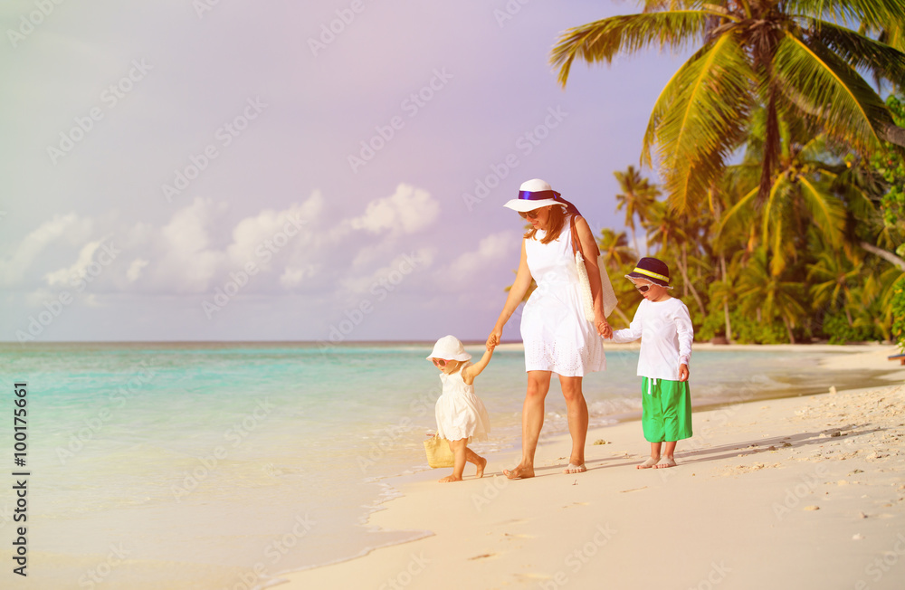 mother and two kids walking on tropical beach