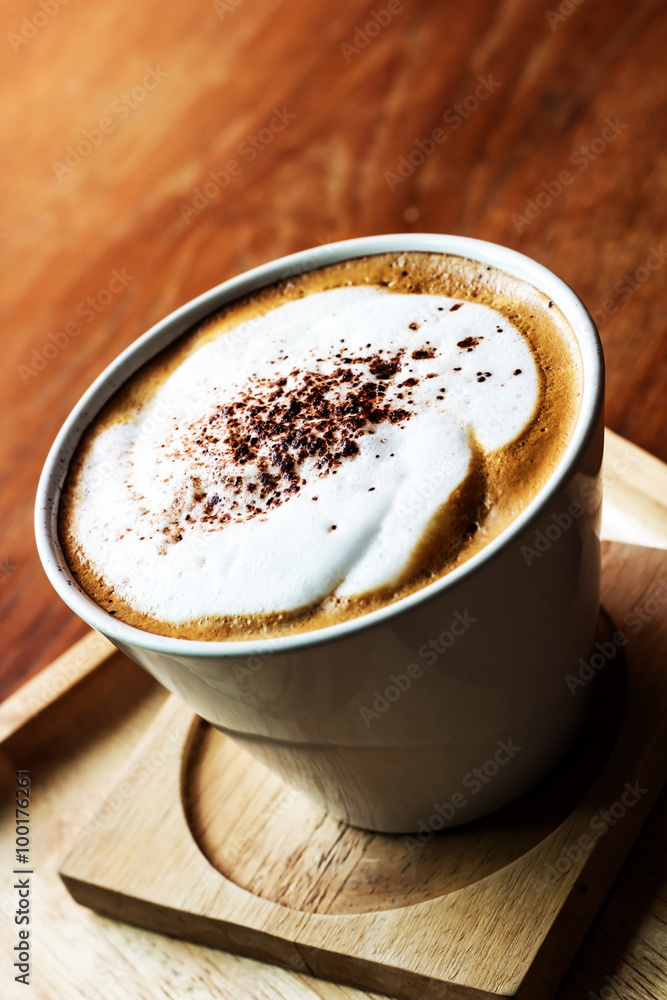 Top view of Cappuccino coffee in a white cup on wooden background. Top view of Cappuccino coffee in a white cup on wooden background.