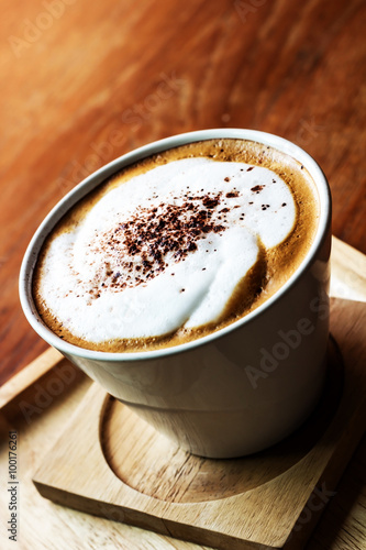 Top view of Cappuccino coffee in a white cup on wooden background.