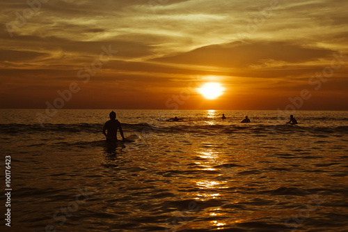 Surfing at Sunset. Young Man Riding Wave at Sunset. Outdoor Active Lifestyle © polinariaegorova