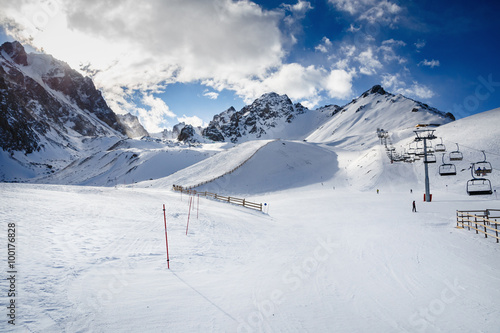Winter mountains panorama with ski slopes and ski lifts. Skiers going down the slope under ski lift. © kulikovan