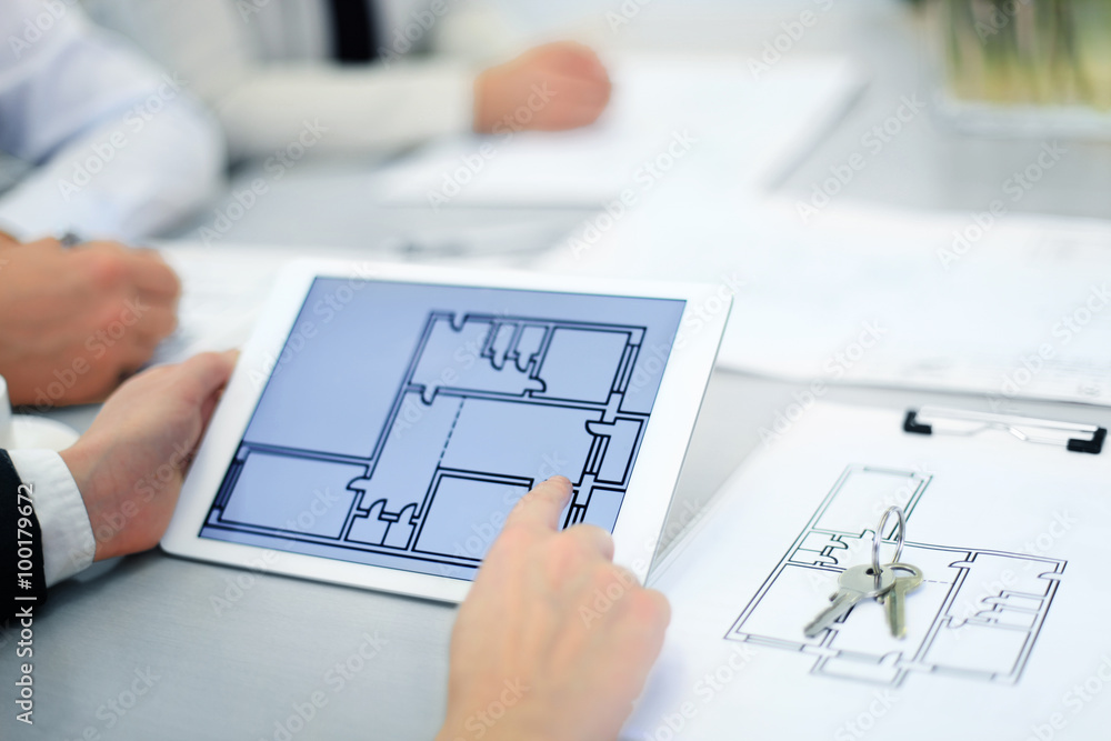 Real-estate agent showing house plans on electronic tablet Real-estate agent showing house plans on electronic tablet