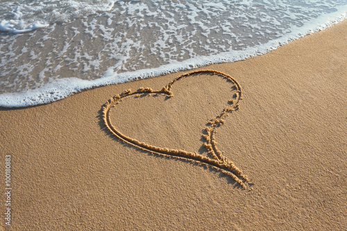 Beautiful heart handwritten in the sand at sunset