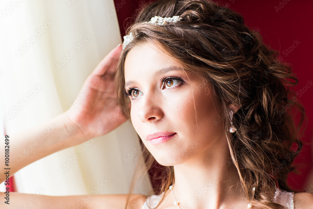 Fototapeta premium Beautiful young bride with wedding makeup and hairstyle in bedroom