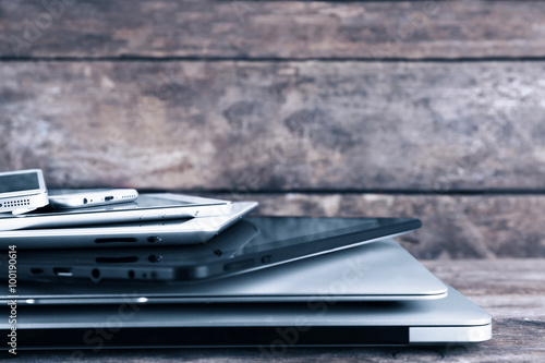 Pile of different modern electronics gadgets on old wooden background