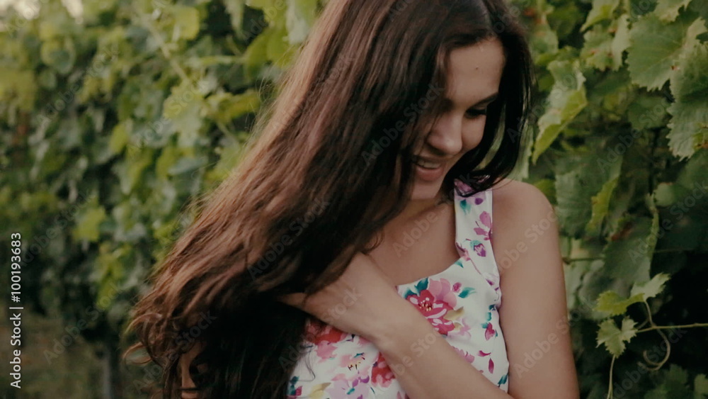 Happy brunette with long curly hair walks through the vineyards in the countryside Happy brunette with long curly hair walks through the vineyards in the countryside