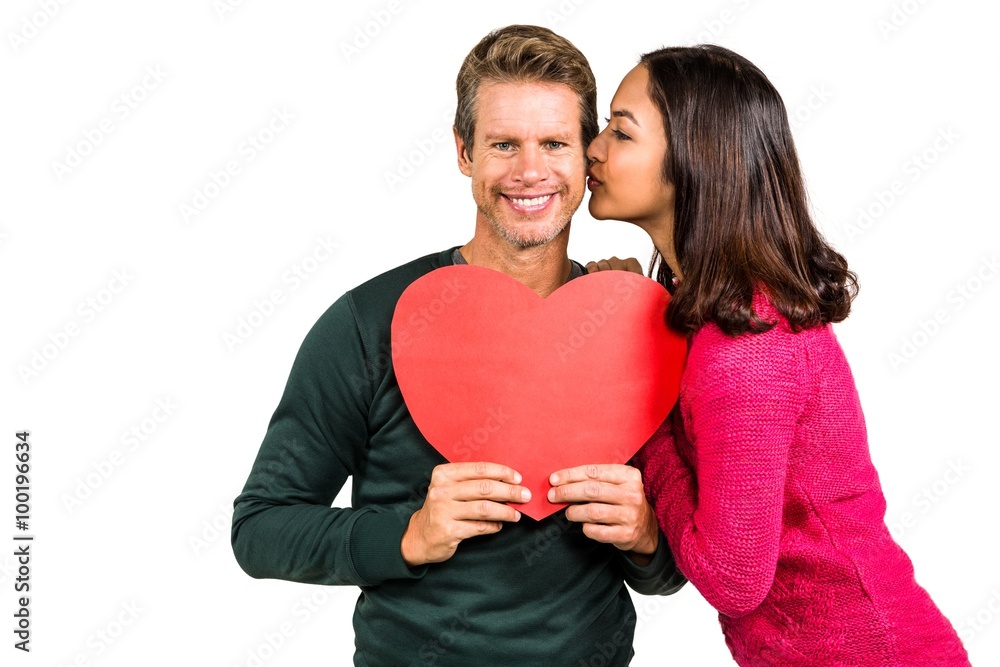 Woman kissing boyfriend with red heart shape Woman kissing boyfriend with red heart shape
