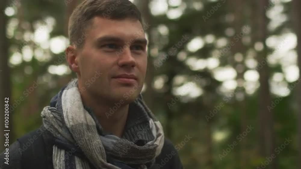 Short haired man in dark autumn coat and a scarf is standing in a forest and looking around. Shot on RED Cinema Camera. Short haired man in dark autumn coat and a scarf is standing in a forest and looking around. Shot on RED Cinema Camera.