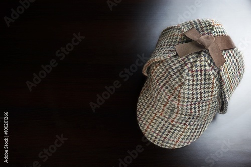 Sherlock  Holmes Deerstalker Hat On The Black Wooden Table