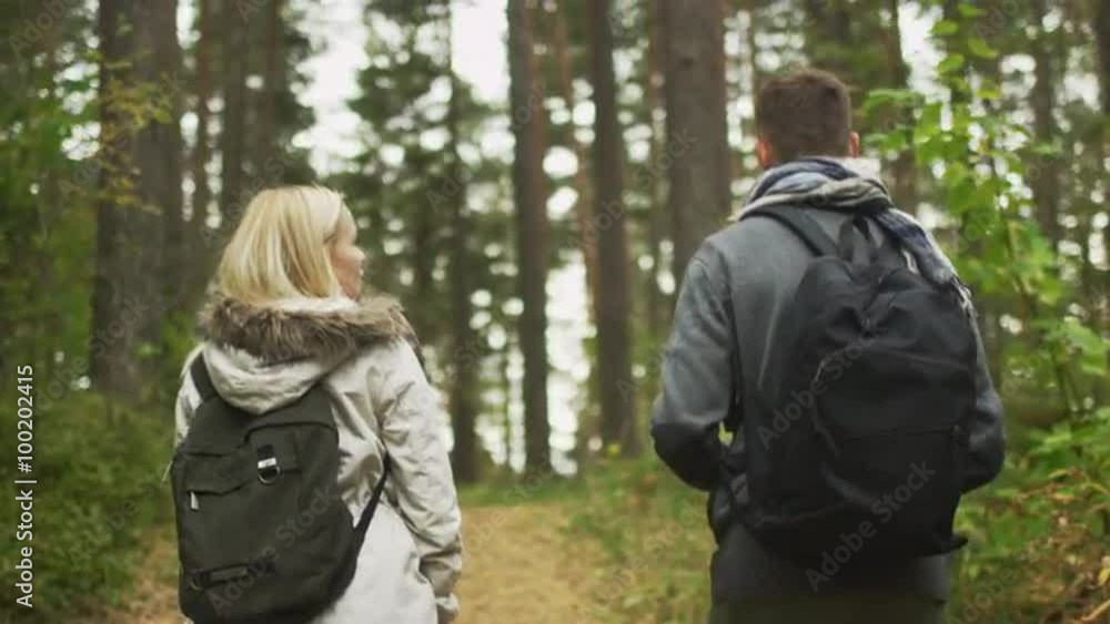 Follow shot from the back of a couple walking in an autumn forest with backpacks. Shot on RED Cinema Camera. Follow shot from the back of a couple walking in an autumn forest with backpacks. Shot on RED Cinema Camera.