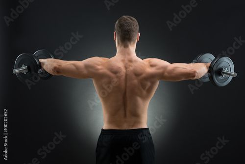 Rear View Of Strong Man Lifting Dumbbells