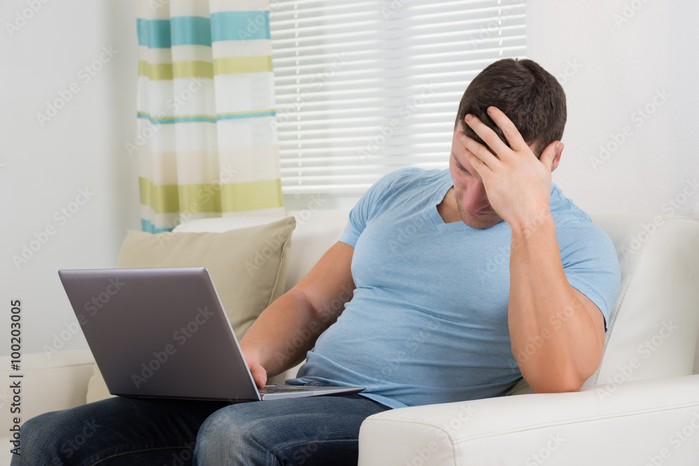 Upset Man With Laptop Sitting On Sofa Upset Man With Laptop Sitting On Sofa