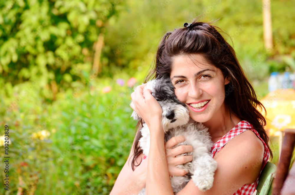smiling young woman hugging her small white poodle dog .Summer time smiling young woman hugging her small white poodle dog .Summer time