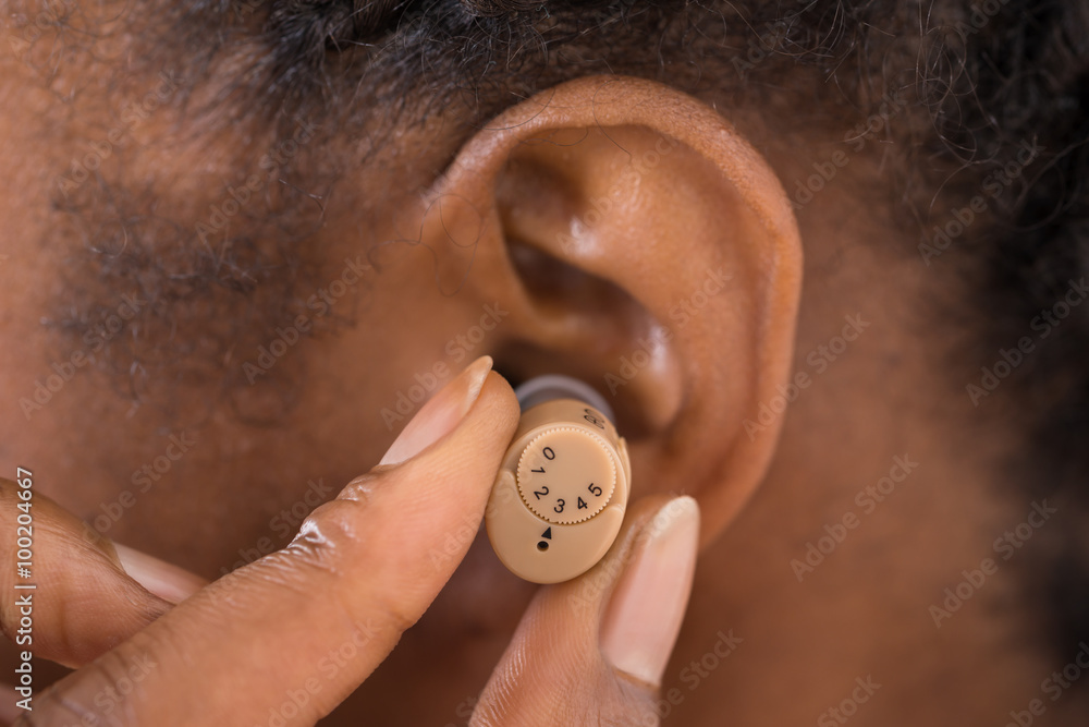 Female Hand Putting Hearing Aid In Ear foto de Stock | Adobe Stock