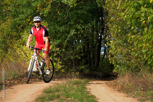 Man is cycling in autumn forest