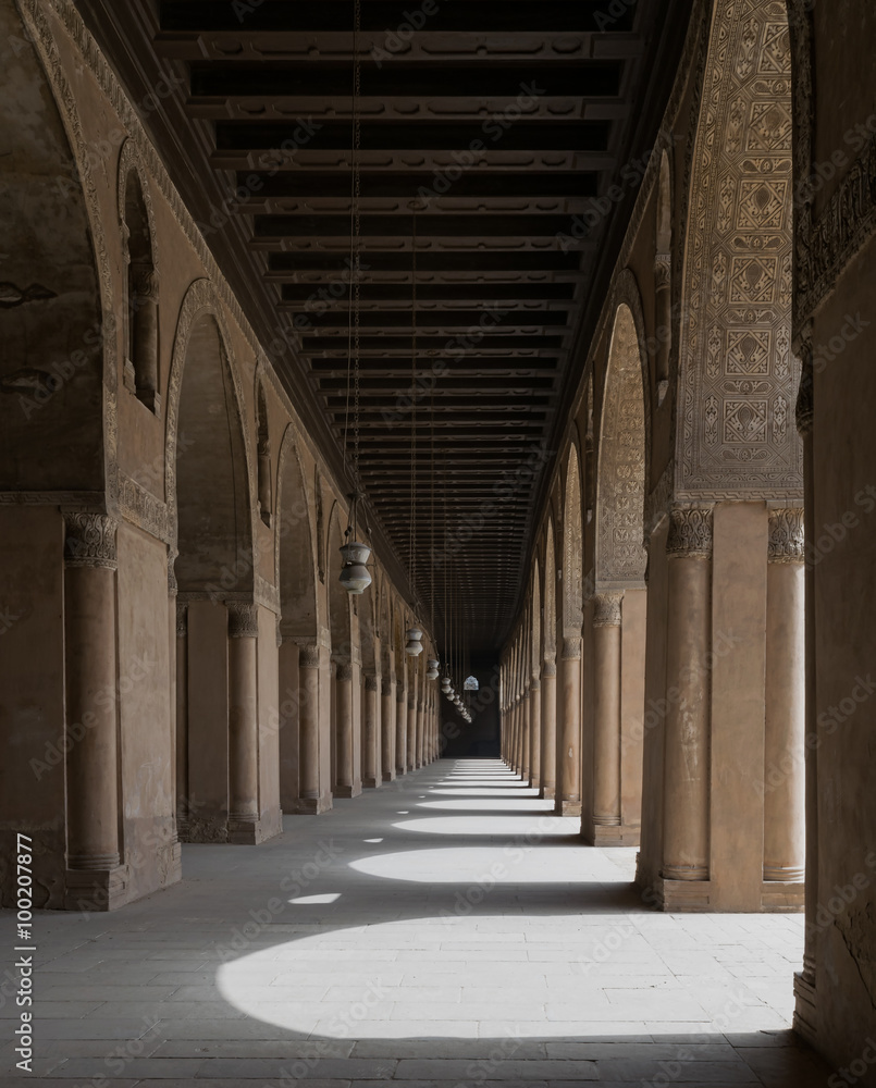 Corridor of a historic mosque with arches and wooden ceiling