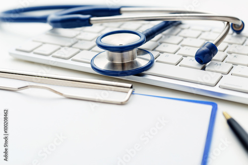 Medical stethoscope on computer keyboard with clipboard