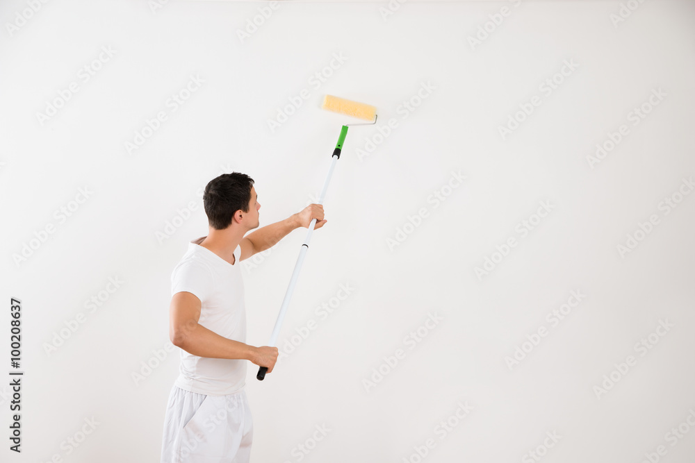 Man Using Paint Roller On White Wall Man Using Paint Roller On White Wall