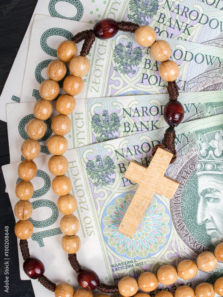 Fototapeta premium Drewniany różaniec leżący na banknotach