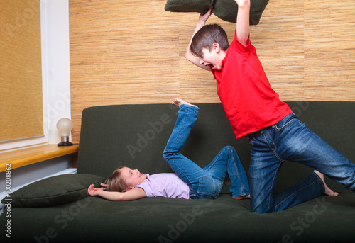 Foto Siblings wearing casual clothes  playing on a green sofa at home fighting with p