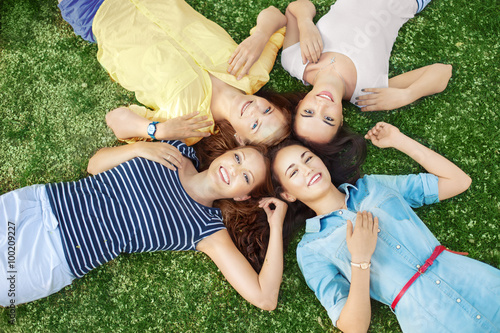 Four girlfriends lying down on the ground and looking up on summer day