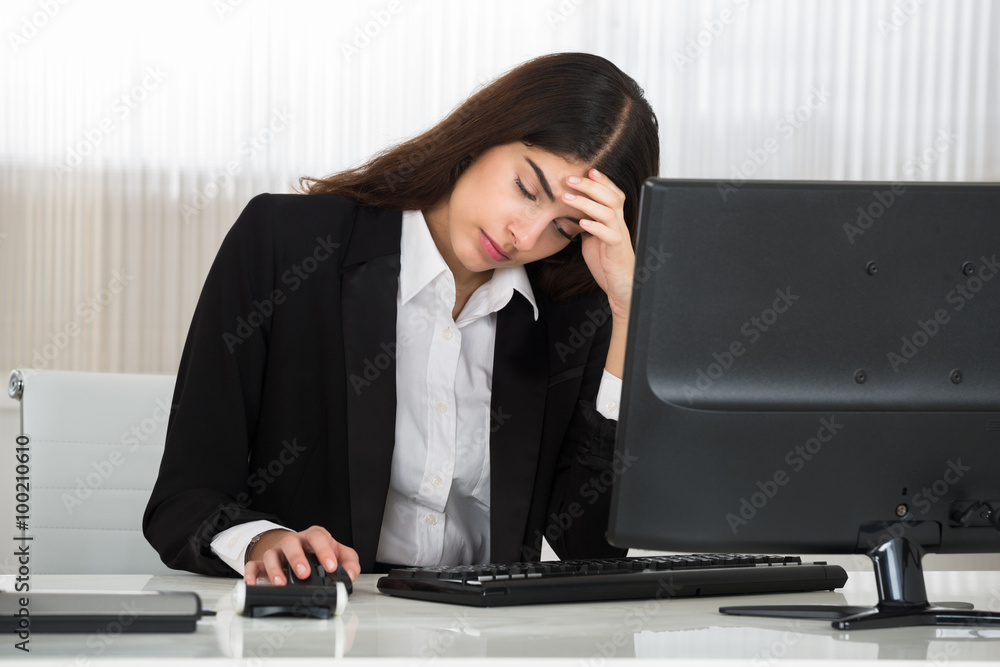 Businesswoman Sitting With Head In Hand At Computer Desk Businesswoman Sitting With Head In Hand At Computer Desk