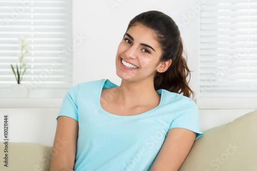 Happy Woman Sitting On Sofa At Home