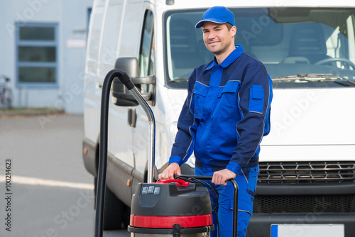 Confident Janitor Standing With Vacuum Cleaner