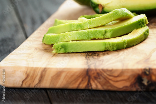 sliced ripe avocados on olive cutting board