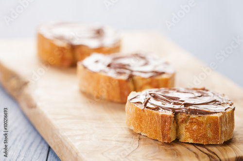 baguette slices with chocolate hazelnut spread on olive board