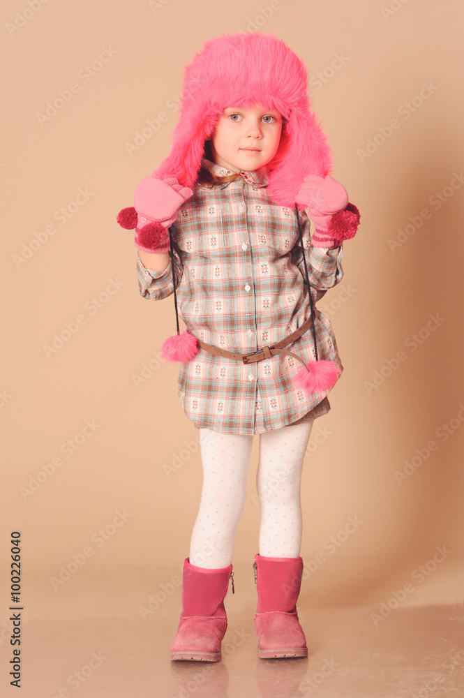 Cute baby girl 4-5 years old wearing trendy stylish winter clothes over beige background