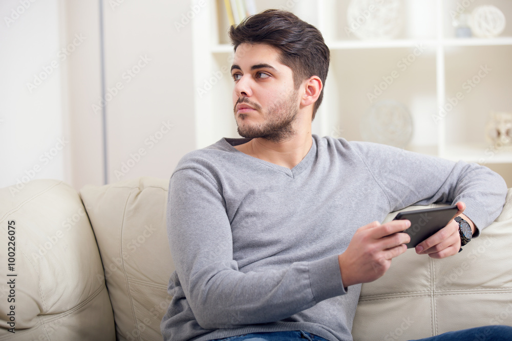 Handsome casual young man using a tablet at home Handsome casual young man using a tablet at home