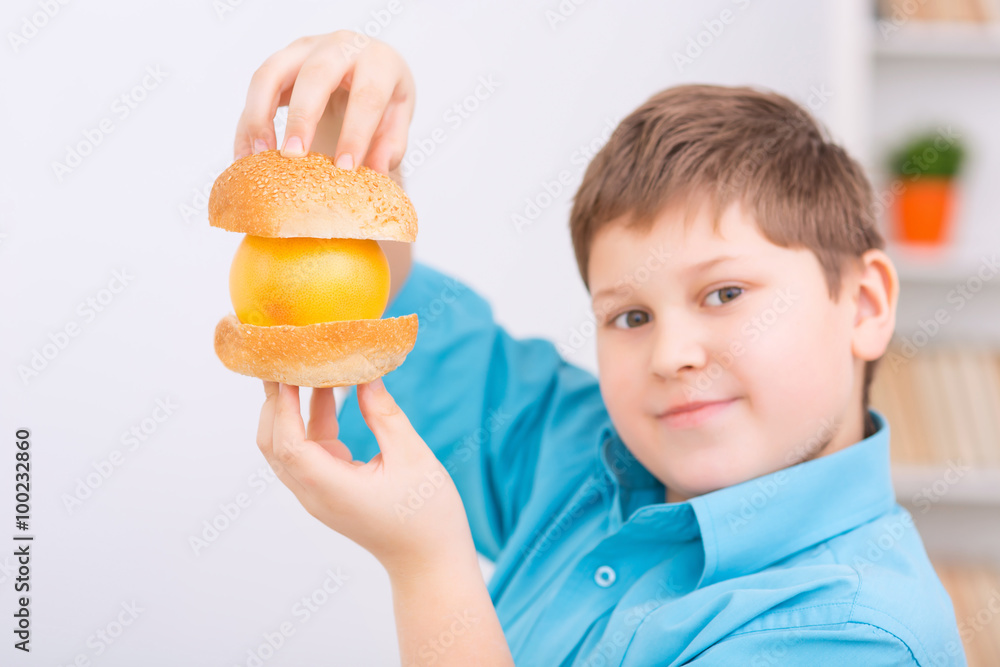 Orange between buns held up by chubby kid. Orange between buns held up by chubby kid.