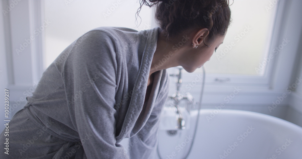 Beautiful young hispanic woman sitting on bathtub testing water