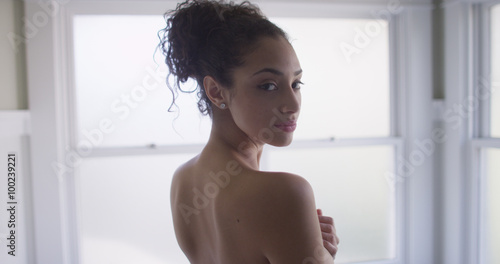 A beautiful mixed ethnic woman with nude back looking over shoul