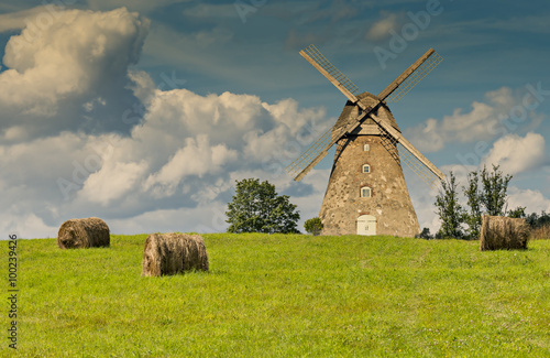 Countryside landscape with rolls of haystacks and old windmill