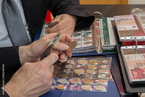 Two numismatists examines  collection of coin