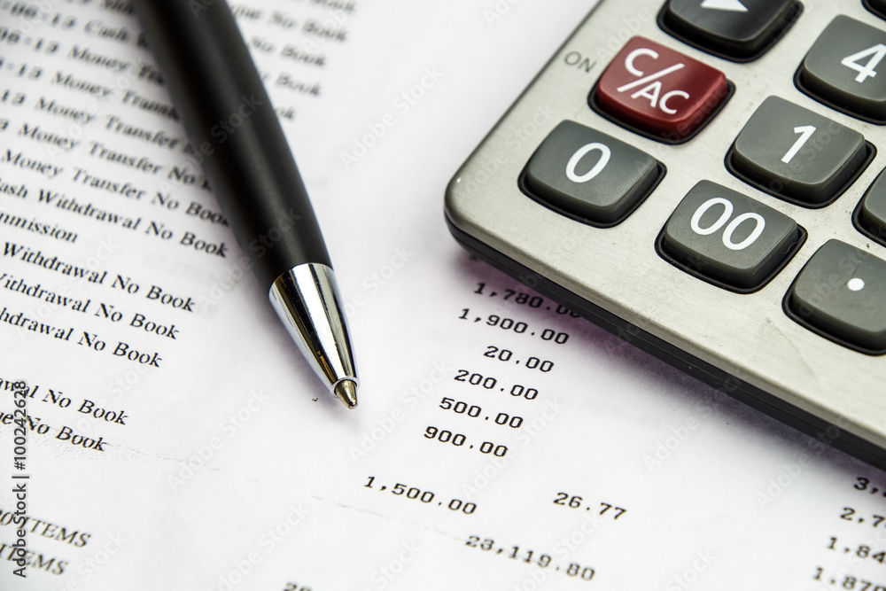 Pen point on bank statement with calculator Pen point on bank statement with calculator