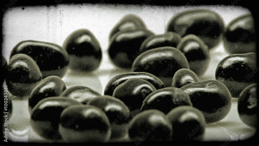 A handful of small black objects roll into view. Vintage stylized video clip. A handful of small black objects roll into view. Vintage stylized video clip.