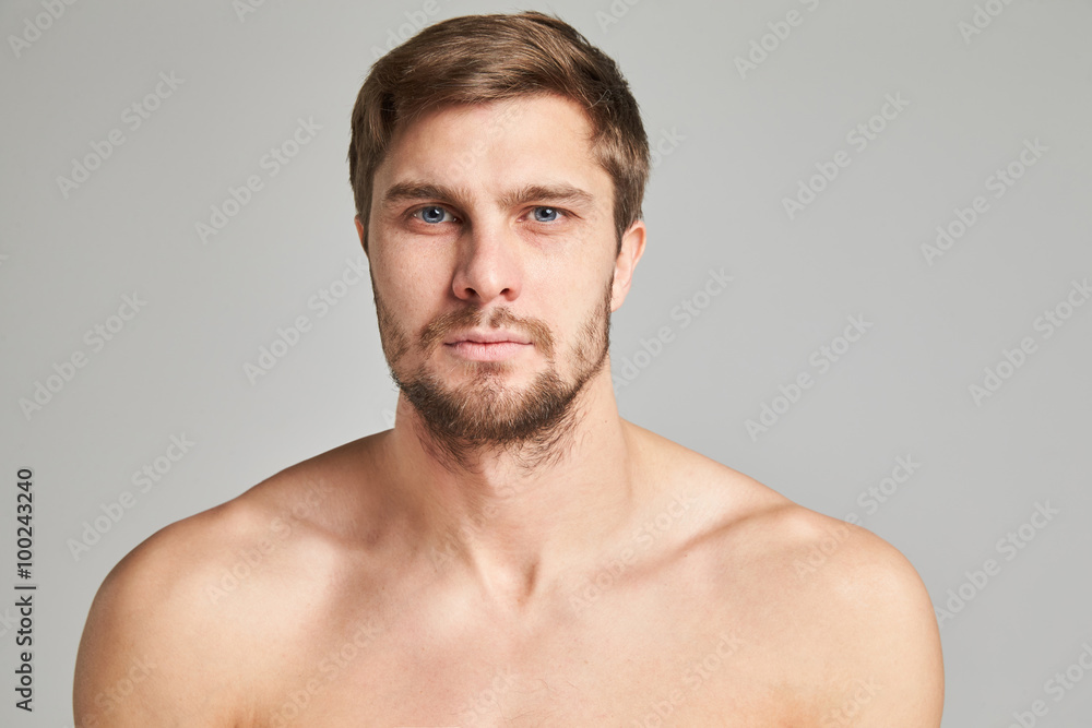 Portrait of a serious young man with bare shoulders on a gray background, powerful swimmers shoulders, beard, charismatic, adult, brutal, athletic Portrait of a serious young man with bare shoulders on a gray background, powerful swimmers shoulders, beard, charismatic, adult, brutal, athletic