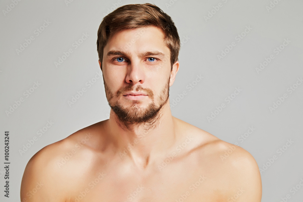 Portrait of a serious young man with bare shoulders on a gray background, powerful swimmers shoulders, beard, charismatic, adult, brutal, athletic, edited photo Portrait of a serious young man with bare shoulders on a gray background, powerful swimmers shoulders, beard, charismatic, adult, brutal, athletic, edited photo
